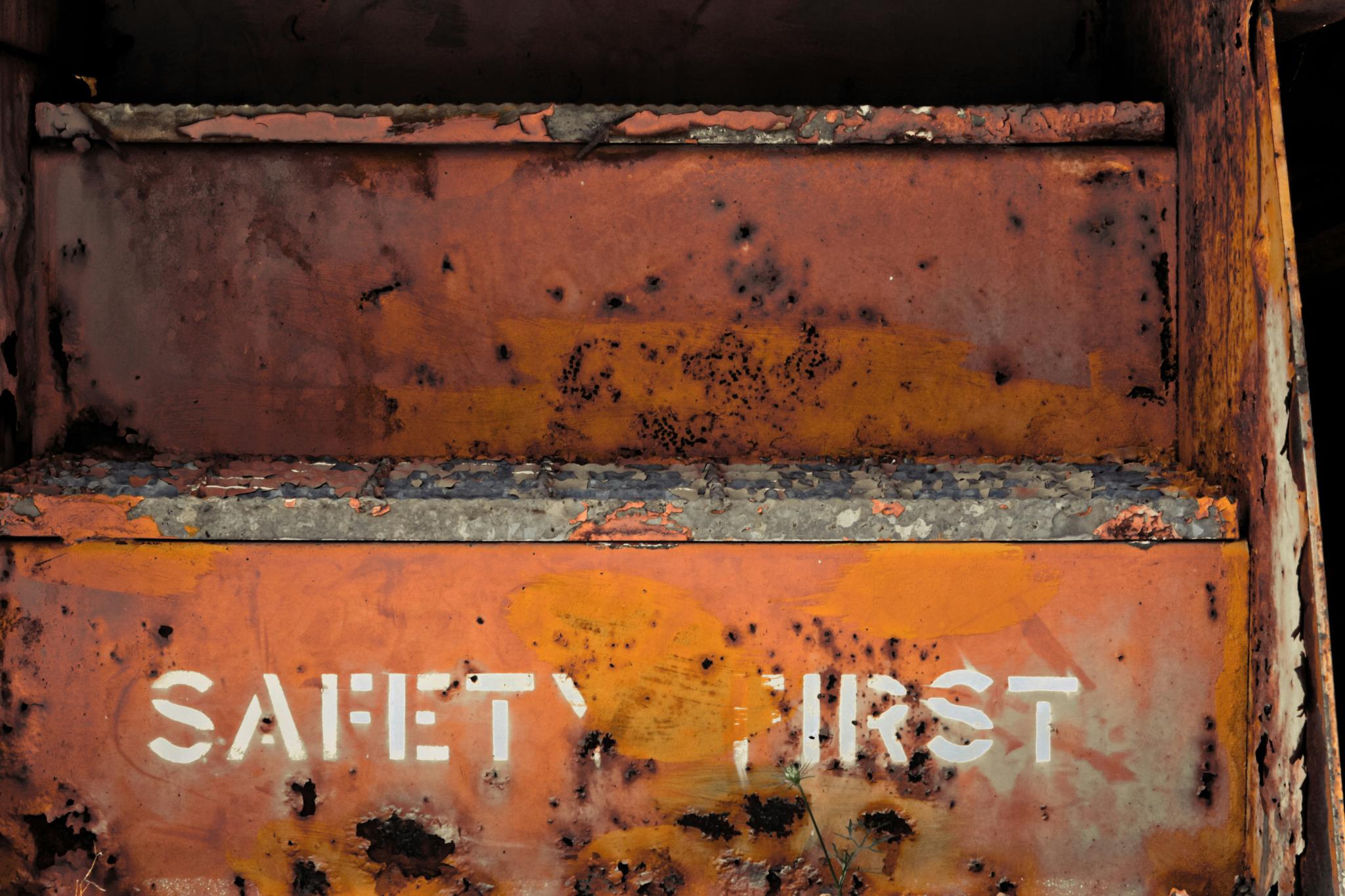 A rusted metal container stencilled with the words “Safety First”, the paint weathered and peeling away.